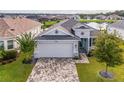 Inviting aerial view of the home showing the paver driveway and manicured lawn at 8492 Hartford Way, Mount Dora, FL 32757