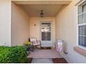 Inviting front porch with a chair, potted plants, and a decorative welcome mat under an overhanging light fixture at 919 Medira Dr, The Villages, FL 32159