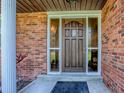 A detailed view of a stained wood front door with sidelights and brick exterior at 111 Cardinal Ln, Eustis, FL 32726