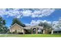 Attractive single-story home features lush landscaping, arched windows and neutral exterior paint at 11301 Via Mari Cae Ct, Clermont, FL 34711