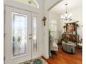 Elegant foyer features a decorative glass door, chandelier, and hardwood flooring at 1446 Arbor Trl, The Villages, FL 32162