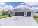 Spacious driveway featuring a palm tree insignia that leads to a charming single Gathering home with a three car garage at 2129 Landrea Loop, The Villages, FL 32163