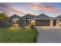 Beautiful single Gathering home with a well manicured lawn and landscaping with a two car garage at sunset at 2129 Landrea Loop, The Villages, FL 32163
