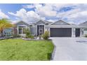 Charming single Gathering home with manicured lawn, colorful flowers, and three car garage at 2129 Landrea Loop, The Villages, FL 32163
