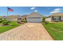 Inviting single-story home with a brick-paved driveway, attached garage, and well-maintained lawn at 3041 Batally Ct, The Villages, FL 32162