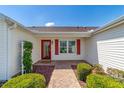Covered front entry featuring red door and shutters, and beautifully manicured landscaping at 3041 Batally Ct, The Villages, FL 32162