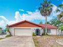 Exterior of a charming single-story home featuring a tile roof, two-car garage and mature palms at 33620 Picciola Dr, Fruitland Park, FL 34731