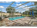 Inviting pool area with a screened enclosure, comfortable seating, and a lush green landscape in the background at 342 Mccormick Ln, The Villages, FL 32162