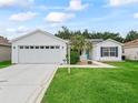 Inviting home featuring a two car garage, pristine lawn, blue shutters and solar panels for energy efficiency at 3534 Auburndale Ave, The Villages, FL 32162