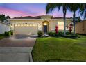 Charming single-story home with a brick driveway, lush lawn, and tropical landscaping at dusk at 3948 Serena Ln, Clermont, FL 34711