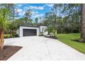 Modern home with a spacious driveway leading to a sleek garage, set against a backdrop of lush greenery at 42191 Cashew St, Eustis, FL 32736