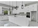 Bright kitchen features white cabinets, a large island, modern pendant lighting, and high-end appliances at 42191 Cashew St, Eustis, FL 32736