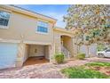 Inviting two-story townhome featuring a private garage, landscaped yard, and a charming brick walkway leading to the entrance at 5492 Compass Pt, Oxford, FL 34484