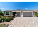 Inviting single-story home with a patterned driveway and beautiful landscaping at 560 Caputo Ct, The Villages, FL 32163