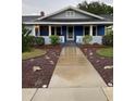 Inviting covered front porch with blue accents and concrete walkway leading to the entrance at 604 N Old Wire Rd, Wildwood, FL 34785