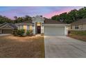 Charming single-story home with a well-manicured front yard, a two-car garage, and a welcoming entrance at dusk at 704 Chelsea Ave, Fruitland Park, FL 34731