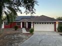 Charming red home with solar panels, a two-car garage, and well-maintained landscaping at 808 Chamberlain Loop, Lake Wales, FL 33853