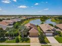 Aerial view of house showcasing well-manicured lawn, landscaping, paver driveway, and tranquil lake at 8387 Bridgeport Bay Cir, Mount Dora, FL 32757