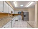 Well-lit kitchen featuring white cabinetry, stone countertops and stainless steel appliances at 903 Belle Oak Dr, Leesburg, FL 34748