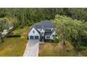 Beautiful two-story home with a manicured lawn, long gray driveway and mature trees at 9134 Mossy Oak Ln, Clermont, FL 34711