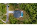 Aerial view of a home with a private pool, patio, long driveway and mature trees at 9134 Mossy Oak Ln, Clermont, FL 34711