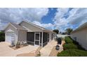 Exterior rear view with a screened lanai area, a patio, and well-maintained landscaping at 971 Margaux Trl, The Villages, FL 32162