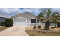 Charming home featuring a well-maintained lawn, a white picket fence, and a two-car garage at 971 Margaux Trl, The Villages, FL 32162
