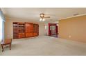 Spacious living room with plush carpet, a ceiling fan, and beautiful wooden built-in shelving at 1110 Fairfax St, Leesburg, FL 34748
