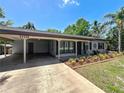 Charming single-story home showcasing a covered carport, well-manicured lawn, and vibrant flower beds at 11114 Lake Eustis Dr, Leesburg, FL 34788