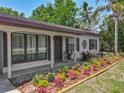 Inviting home entrance with stylish landscaping, dark shutters, and mature plants at 11114 Lake Eustis Dr, Leesburg, FL 34788