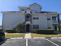 A three-story condo building features gray exterior paint, white stairs, and lush green landscaping with a parking lot at 14049 Fairway Island Dr # 118, Orlando, FL 32837