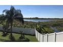 Spacious backyard with a white fence and serene pond view, offering privacy and natural beauty at 1730 Ridgemoor Dr, Mascotte, FL 34753