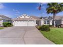 Daytime view of this property, featuring a three-car garage, manicured landscaping, and an American flag at 2124 Hames Ln, The Villages, FL 32162