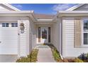 This home welcomes you with its covered front door, adorned with a green welcome mat and beautiful flowering bushes at 2124 Hames Ln, The Villages, FL 32162