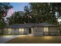 Charming single-story home with a well-maintained lawn, mature trees, and a welcoming driveway at dusk at 227 Oak Rd, Winter Springs, FL 32708