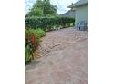 A partially shaded back patio featuring decorative concrete stones is accented with bordering greenery and outdoor seating at 2750 Coral Reef Way, Tavares, FL 32778