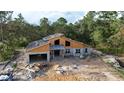 New home construction featuring block walls, wood framing, and an attached garage in a wooded community at 30551 Saffron Ave, Eustis, FL 32736
