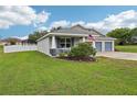 Charming single-story home showcasing a manicured lawn, front porch, and stylish gray accents at 395 S Dixie Dr, Howey In The Hills, FL 34737