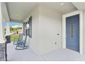 Inviting front porch featuring a blue front door, rocking chairs, and stone-accented columns at 395 S Dixie Dr, Howey In The Hills, FL 34737