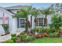 Charming home featuring beautiful landscaping with palm trees, flowers, and an American flag at 4087 Capland Ave, Clermont, FL 34711