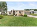 Charming single-story home with a lush green lawn and an attached two-car garage at 5075 China Sea Dr, Tavares, FL 32778
