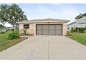Attached two-car garage featuring a concrete driveway and manicured landscaping at 5075 China Sea Dr, Tavares, FL 32778