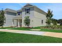 Side view of a two-story home featuring green grass, young tree and a landscaped area at 5105 Blanket Flower St, Apopka, FL 32712