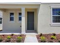Inviting front entrance featuring a gray door, manicured landscaping, and a cozy porch, perfect for a welcoming first impression at 5105 Blanket Flower St, Apopka, FL 32712
