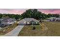 Twilight view of a single-story home with a well-maintained lawn and an attached two-car garage at 529 Ed Douglas Rd, Groveland, FL 34736