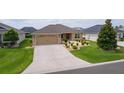 Inviting single-level home showcasing a spacious driveway and a neatly landscaped front yard for a welcoming appeal at 5596 Cedar Waxwing Dr, The Villages, FL 32163