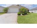 Home with a unique compass rose driveway, attached garage, and manicured landscaping at 744 Shelton St, The Villages, FL 32163