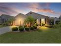 Inviting home with manicured lawn, landscape lighting, and palm trees, captured at dusk at 744 Shelton St, The Villages, FL 32163