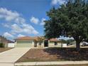 Charming one-story home with a well-kept lawn, featuring a two-car garage and mature landscaping at 8025 Cardinal Winds Ln, Mascotte, FL 34753