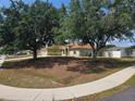 Lovely one-story home with mature trees, featuring a two-car garage, green lawn, and charming curb appeal at 8025 Cardinal Winds Ln, Mascotte, FL 34753